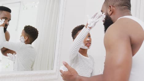 Feliz-Padre-E-Hijo-Afroamericanos-Aplicando-Crema-De-Afeitar-En-La-Cara-En-El-Baño,-En-Cámara-Lenta