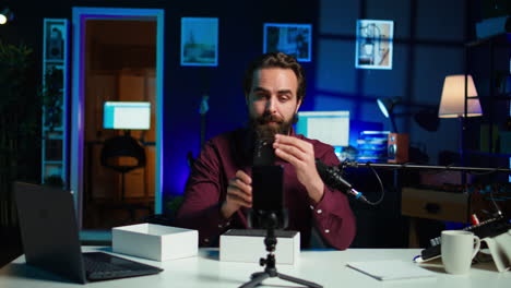 la estrella de los medios en un estudio iluminado con neón presenta un teléfono móvil del video de patrocinio de la marca