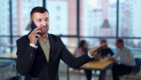 business talk on the phone in office. confident businessman speaking on the phone and is very active and lively. business team sitting at desk and having conversation at backdrop.