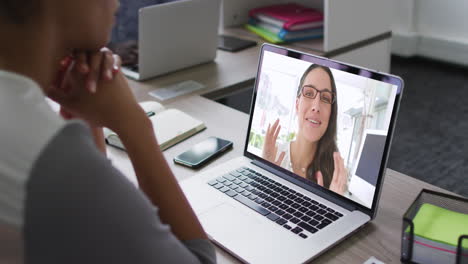 mujer afroamericana teniendo una videoconferencia en una computadora portátil con una colega de oficina en la oficina
