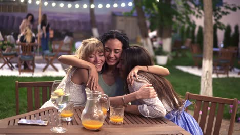 Meeting-girlfriends-in-a-cafe---two-beautiful-girls-kissing-her-friend-in-the-middle,-smiling