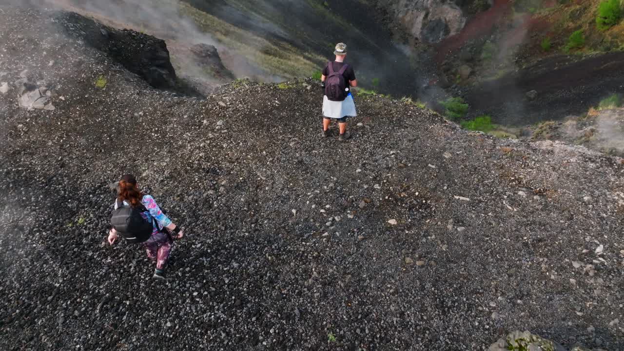 Woman hiker raises hands in joy atop Parícutin Volcano crater surrounded by volcanic steam. Mexico, Michoacan state.