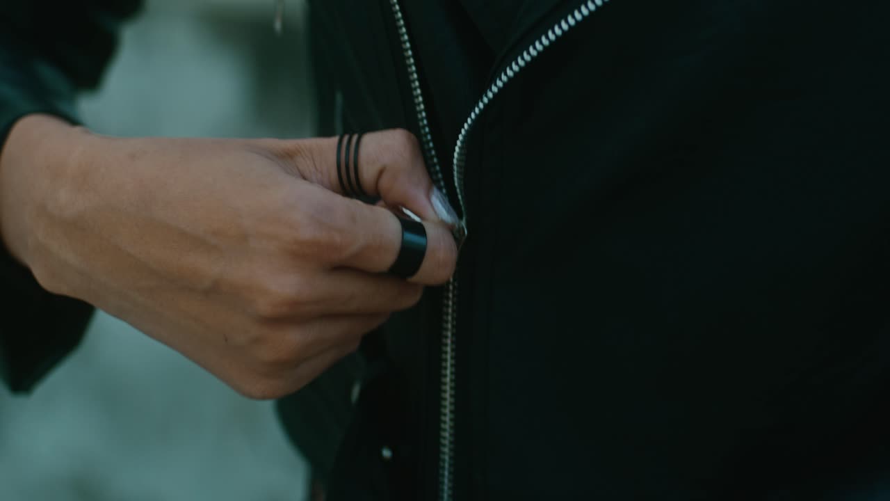 Woman zipping a black leather jacket