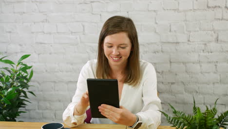 una feliz mujer de negocios comerciante de la bolsa de valores ganando con una tableta en una oficina jugando un juego