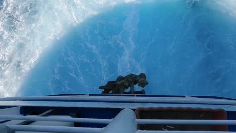 overhead view over railing at stern of ferryboat with water wake from propellers