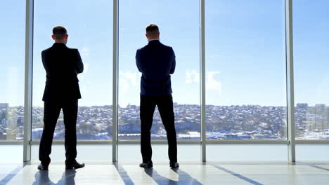 Succesfull businessman looking into modern office window. Back view of thoughtful businessman.