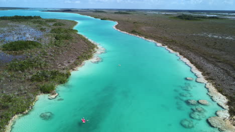 Aerial-shot-of-kayak-on-turquoise-blue-Los-Rapidos-in-Bacalar-Mexico-on-a-sunny-day,-aerial---Aerial-shot-of-boats
