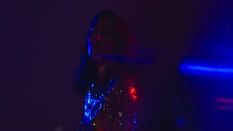 primer plano de una mujer en un bar nocturno o discoteca bailando y divirtiéndose mirando a la cámara