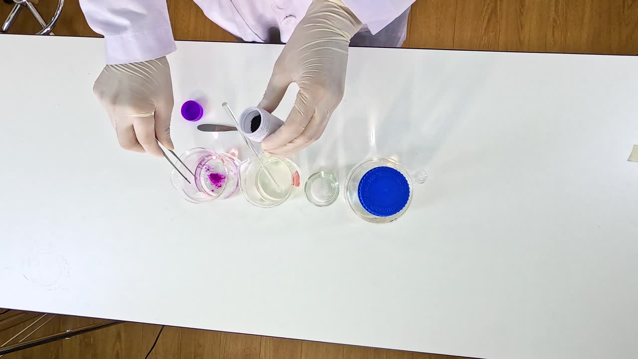 A scientist demonstrates a color change experiment using potassium permanganate on a white table with clear lighting