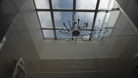 glass ceiling serving as a light well to a magnificent modern bathroom, luxurious and tiled, beautiful chandelier, modern bath