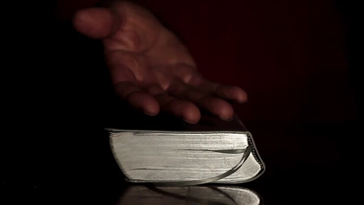 praying to god with hands together with bible and cross Caribbean man praying with black background stock video