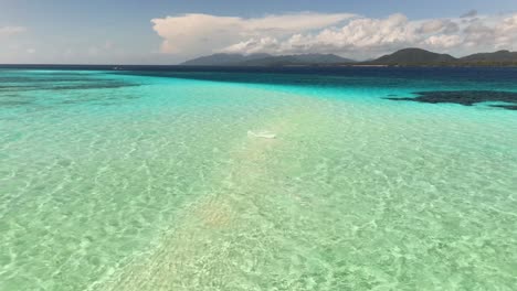 pristine shallow turquoise waters stretch across the candaraman sand bar in balabac, palawan, philippines, revealing a stunning blend of colors, coral patches, and distant mountainous islands