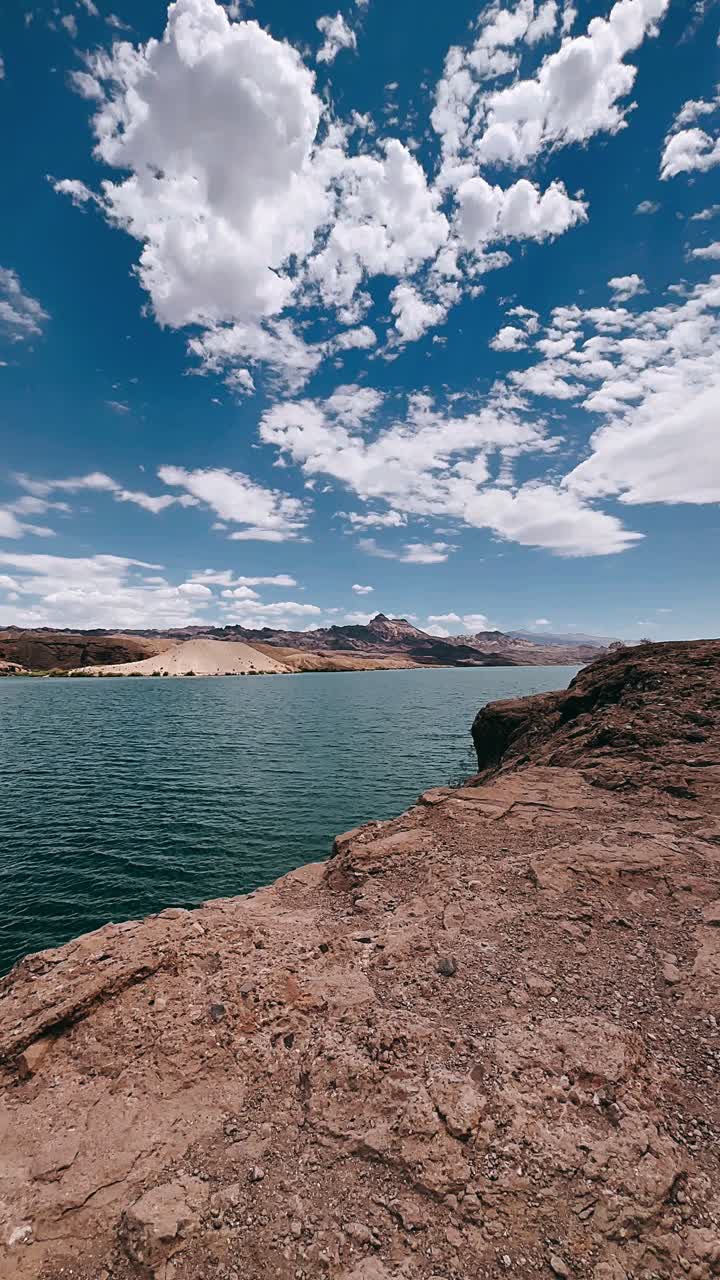 vista panorámica de la orilla del lago con montañas y nubes