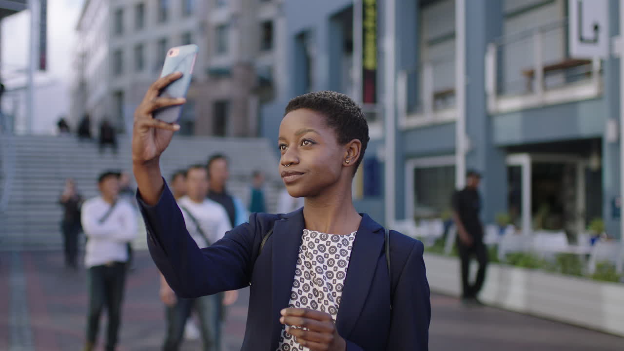 portrait of pretty african american business woman posing taking selfie photo using smartphone in city