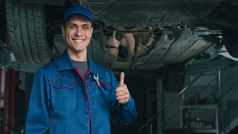 happy mechanic giving thumbs up under a car