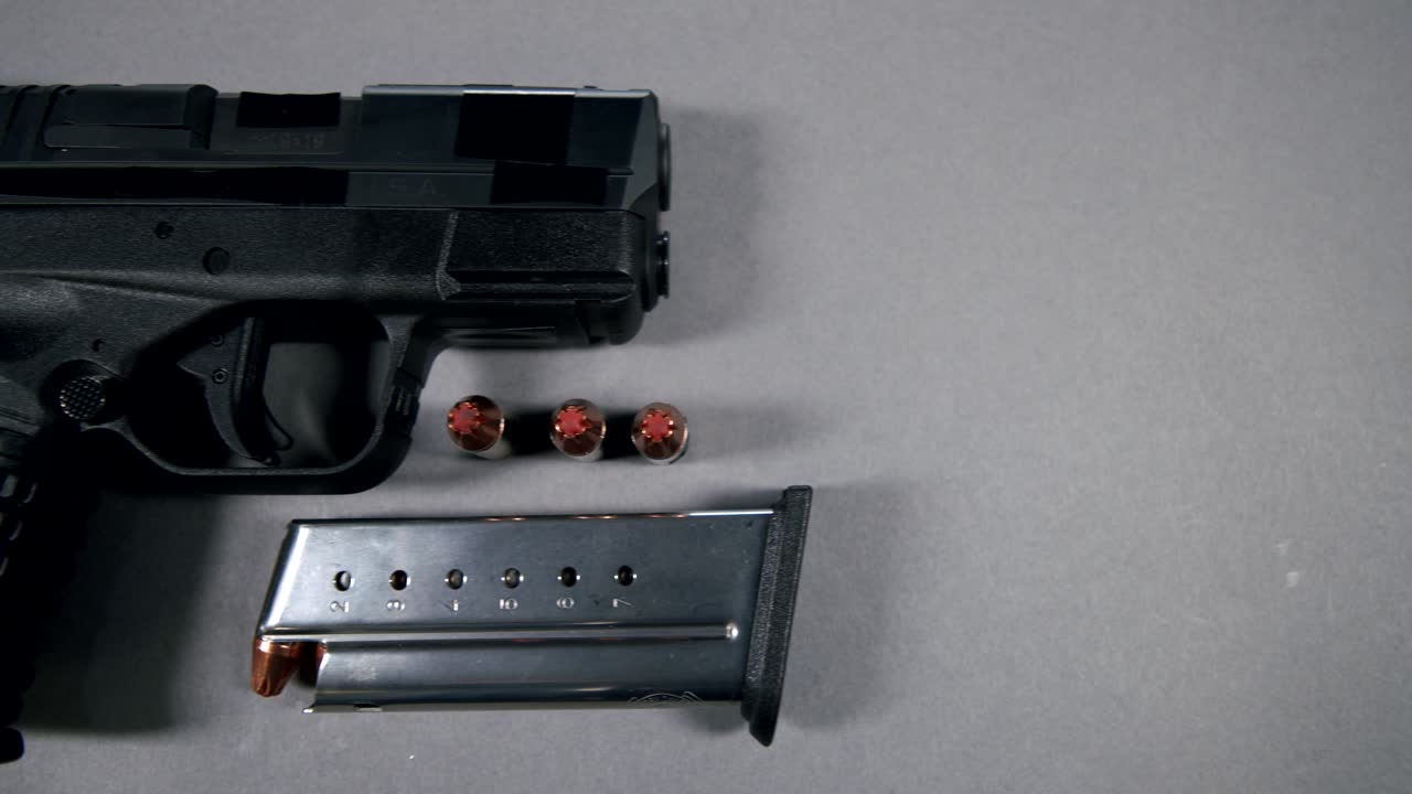 black Semi-Automatic 9mm Handgun on gray background with Loaded Magazine and Bullets, right hand side view, slow pan right to left, 4k