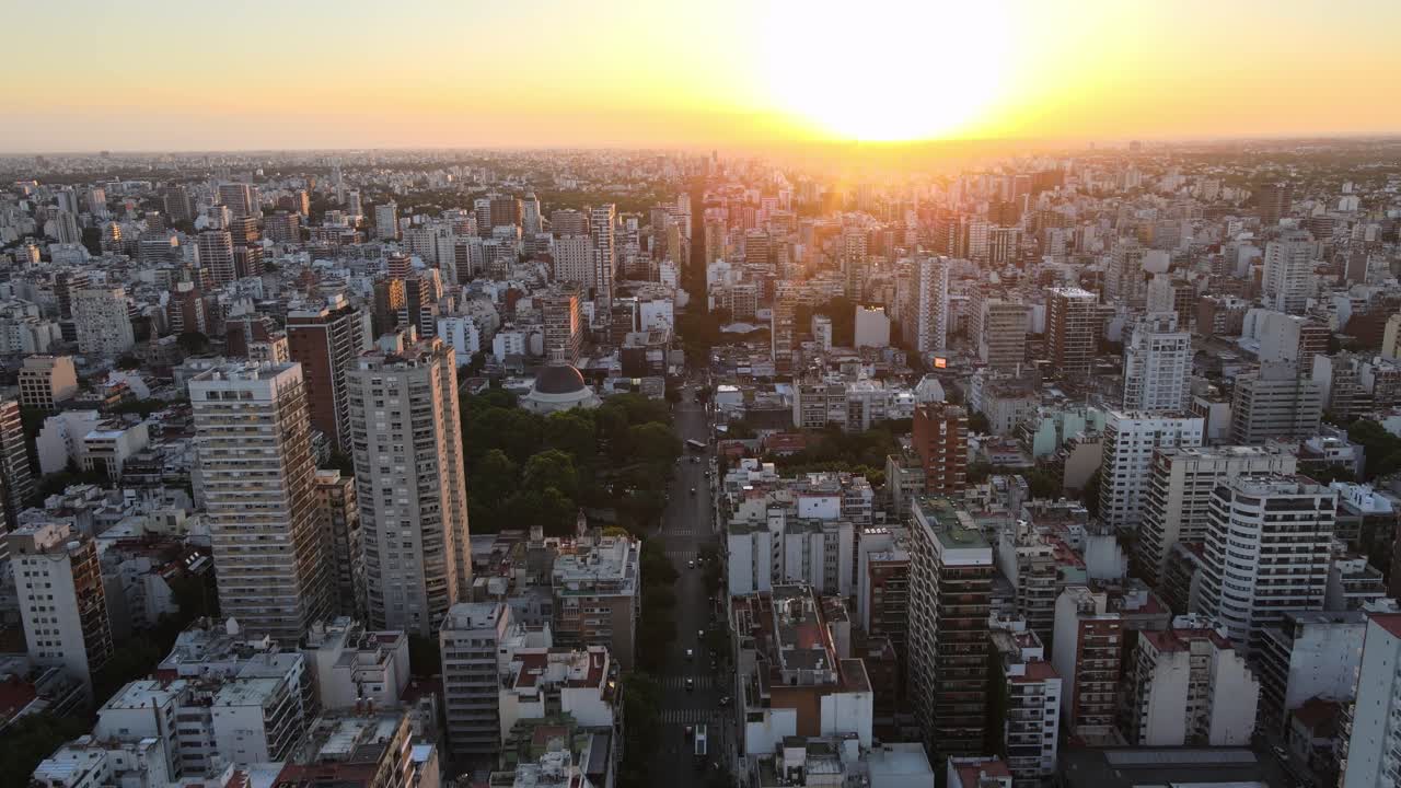 dolly volando sobre los edificios altos del barrio de belgrano al atardecer con sol brillante en el fondo, buenos aires, argentina