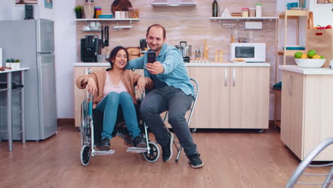 mujer positiva en silla de ruedas y marido tomando una selfie