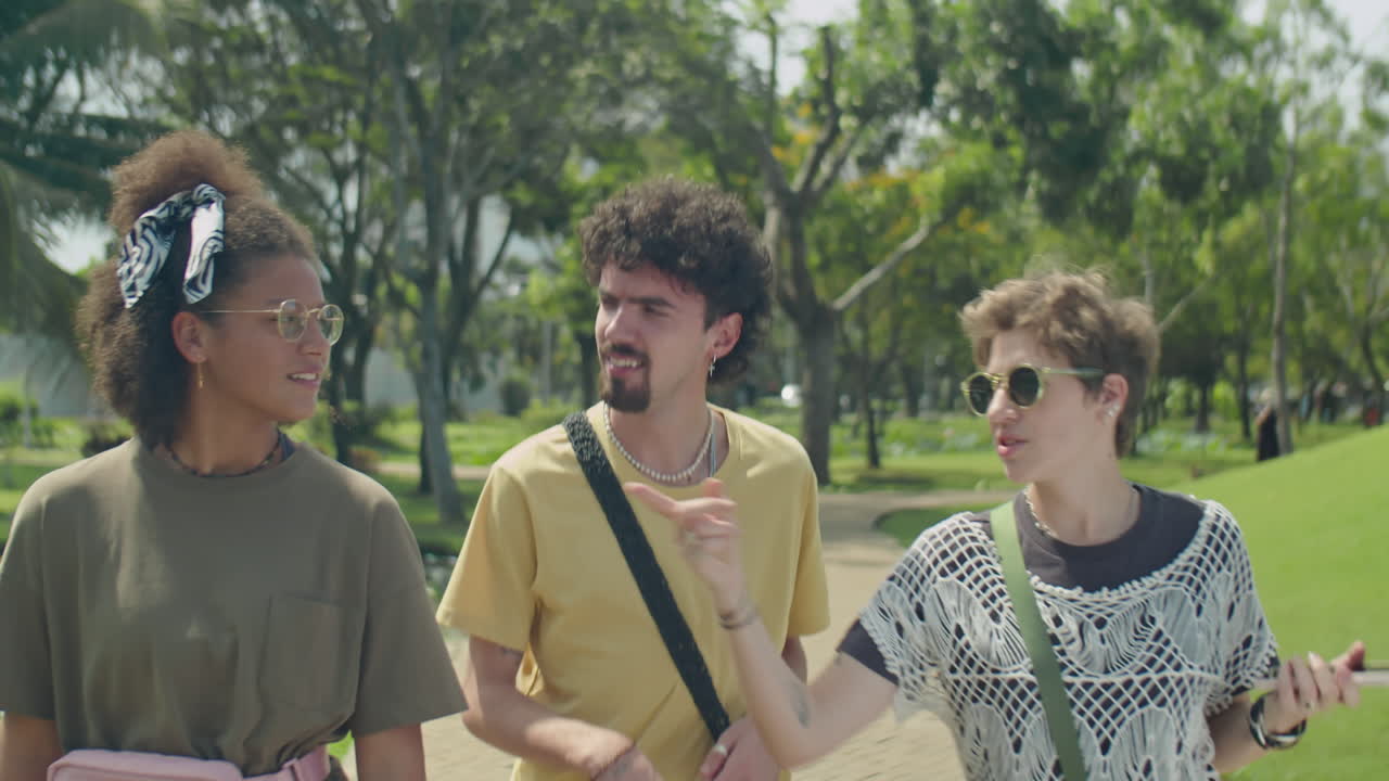 Group of Young Friends Chatting while Walking in Park