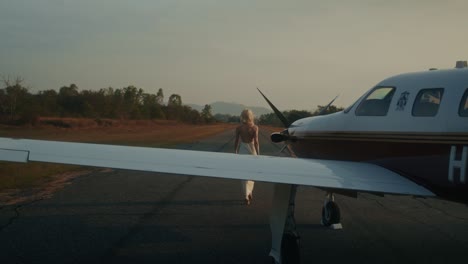 woman walking towards a private plane at sunset