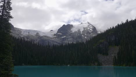 Lagos-Joffre,-Pemberton,-Columbia-Británica,-Canadá---Una-Vista-De-Un-Sereno-Lago-Azul-Rodeado-De-Exuberante-Vegetación,-Con-Una-Montaña-Cubierta-De-Nieve-Adornando-El-Fondo---Plano-General