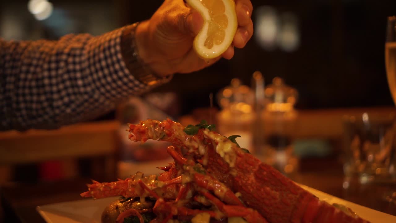 고급 레스토랑에서 삶은 뉴질랜드 가재에 레몬을 쥐어 짜다 - 클로즈업