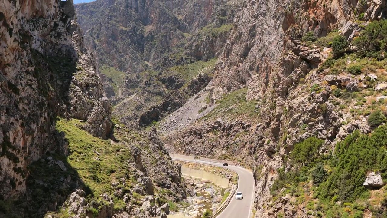 Vista aerea con drone di una strada di montagna che si snoda tra le ripide scogliere rocciose di una gola impervia, Gola di Kourtaliotiko, Grecia