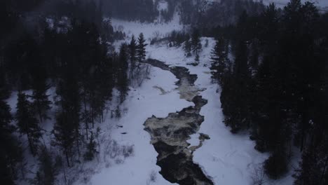 aerial view of frozen river in snowy forest