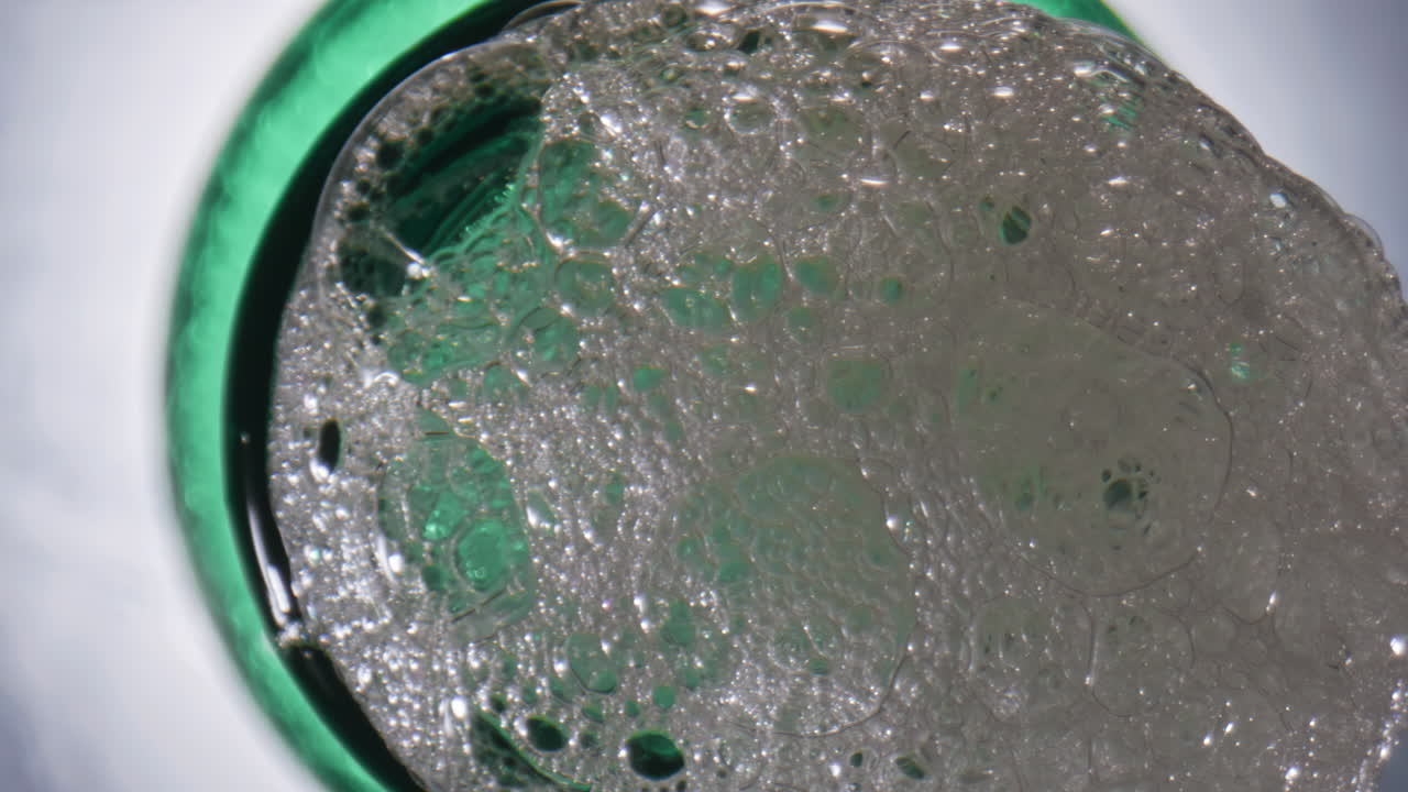 Nærbilde av boblende glass med håndverksdrikk. Alkoholholdig lagerøl danner mye skum i flasken.