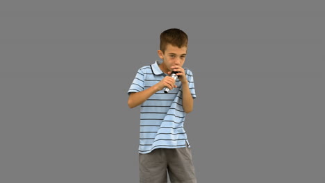 Little-boy-holding-a-microphone-and-singing-on-grey-screen