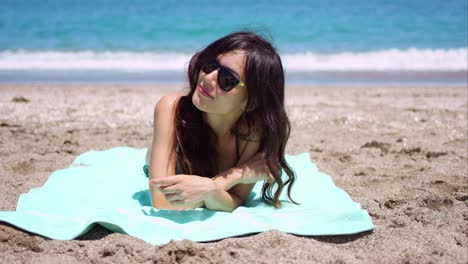 Pretty-woman-in-sunglasses-sunbathing-on-a-beach