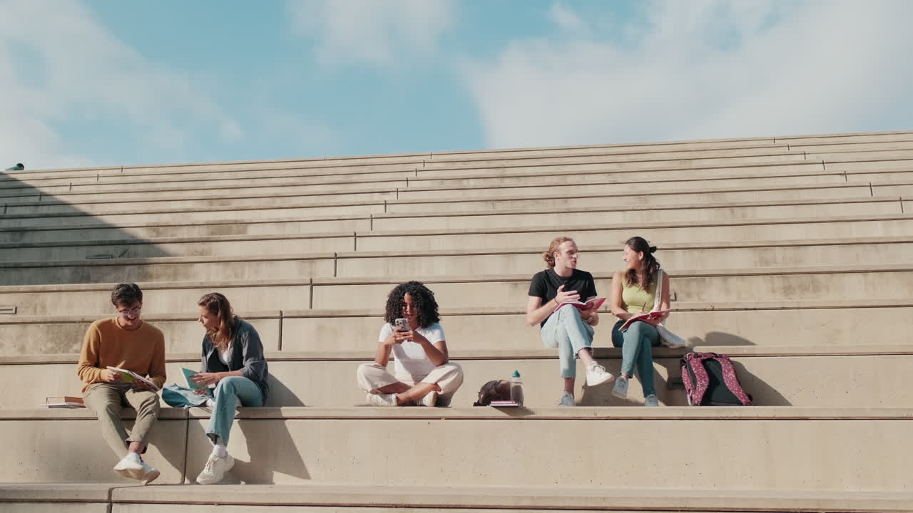 Millennial-gruppe med glade, unge studentvenner som sitter utendørs