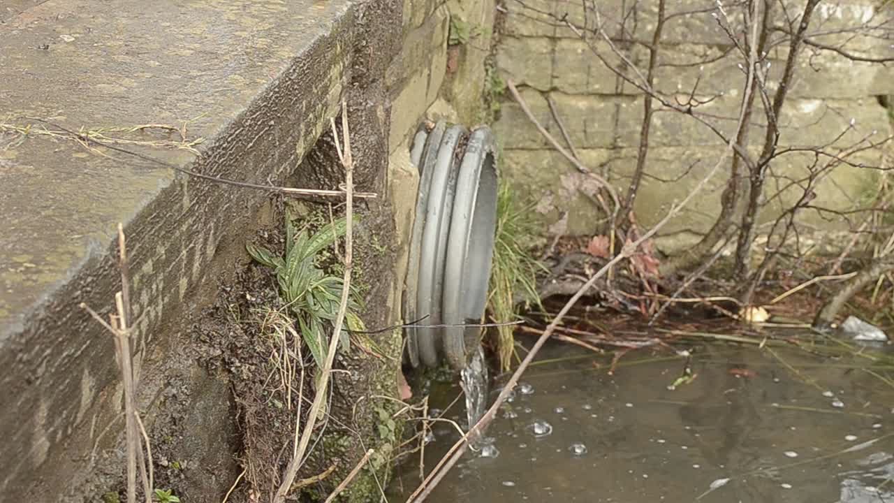 물이 금속 파이프에서 개울로 흐릅니다.