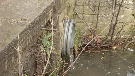 Water-flows-from-metal-pipe-into-stream