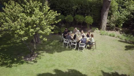 amigos jóvenes reunidos alrededor de la mesa en el patio trasero