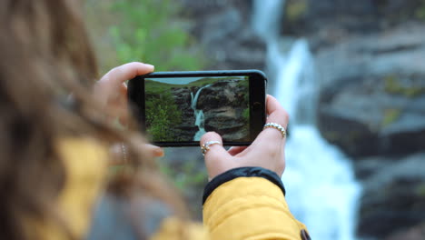 person taking photo of waterfall