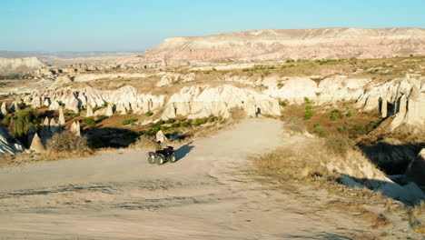 mujer conduce quad a la cima de la colina para ver el valle del amor en el fondo de goreme, turquía