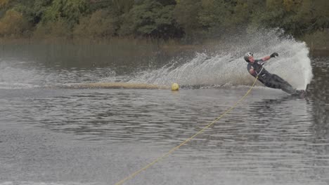 young athletic man cuts around buoy slalom ski