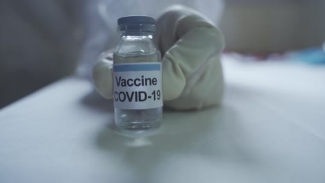 hand of a medical worker wearing ppe kit and glove showcasing covid 19 vaccine