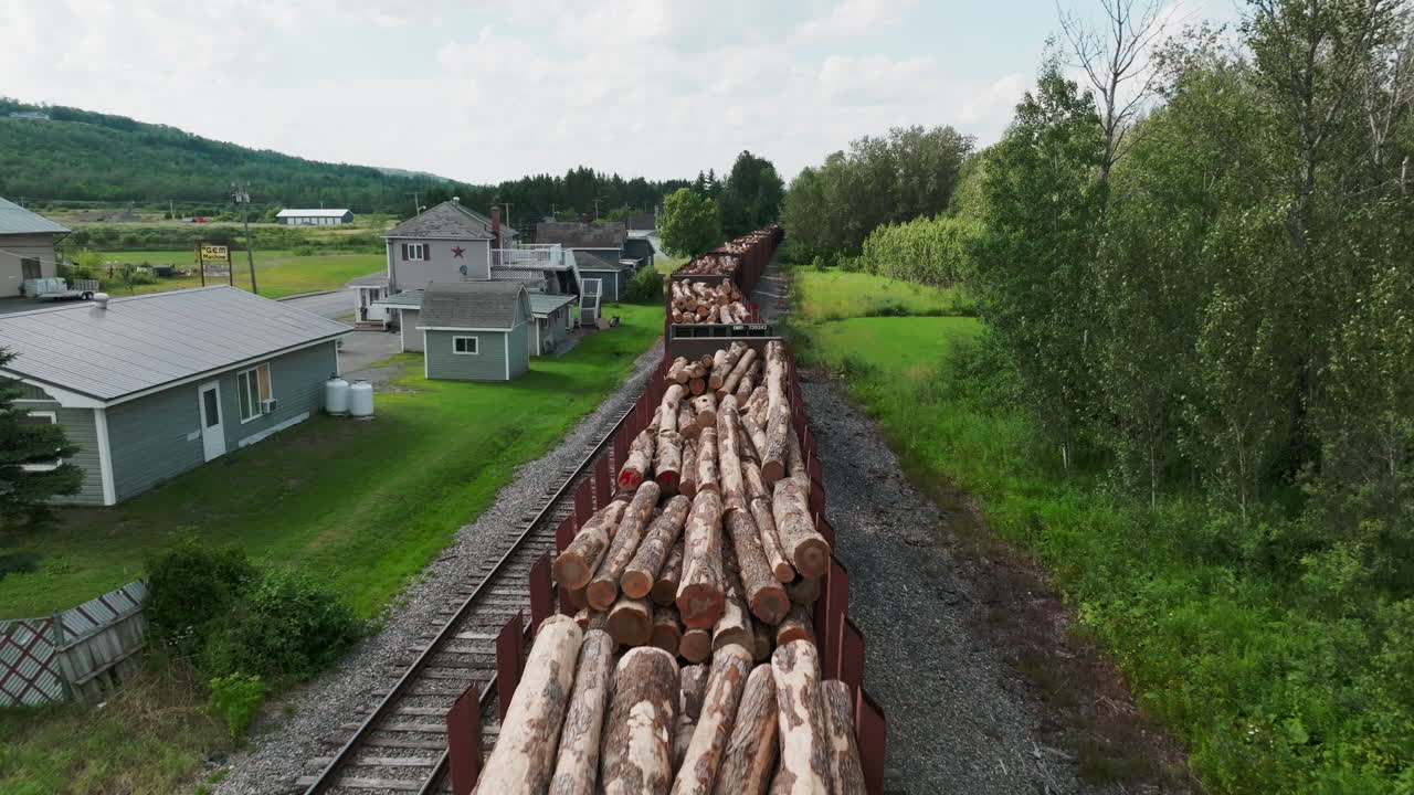 Low Aerial View of Stationary Freight Train Loaded with Lumber, Adjacent to Residential Homes in Rural Maine