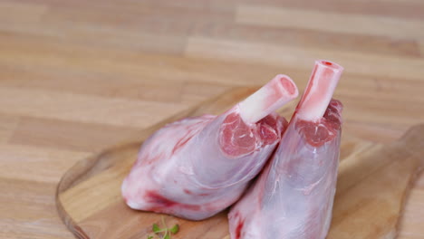 two lamb shanks on wooden cutting board