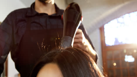 mujer secándose el cabello con un secador de pelo
