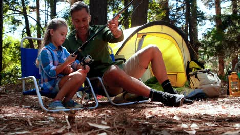 father teaching son to use fishing rod in the park