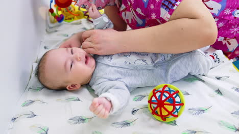 pediatrician applies device to baby's ear. lovely kid doesn't like doctor's check up. medical specialist shows the toy to distract a baby.