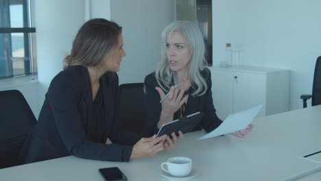 focused female professionals discussing and analyzing reports