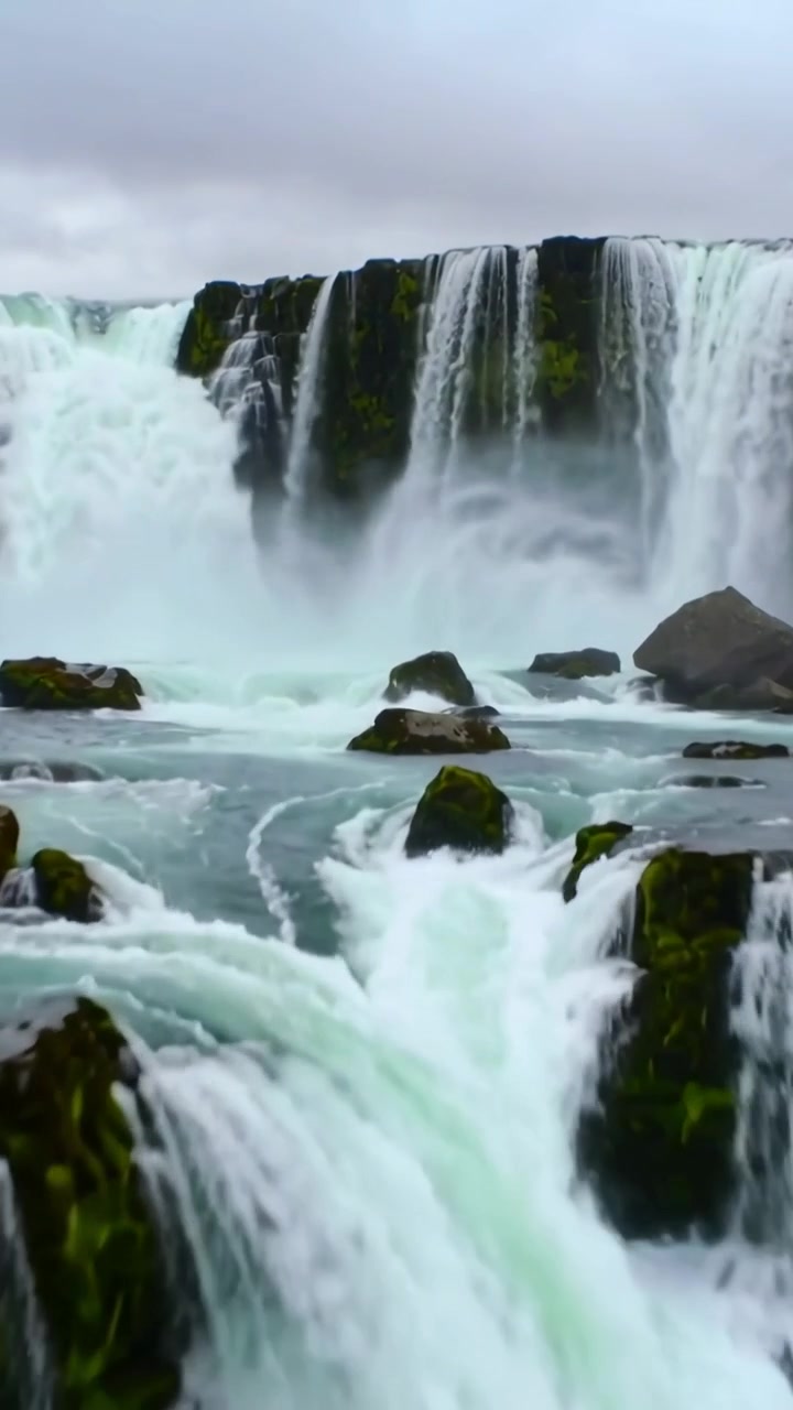 Video verticale: Cascata a più livelli che scorre, rivelando massi muschiosi e schiuma nel fiume, con panoramica della telecamera.