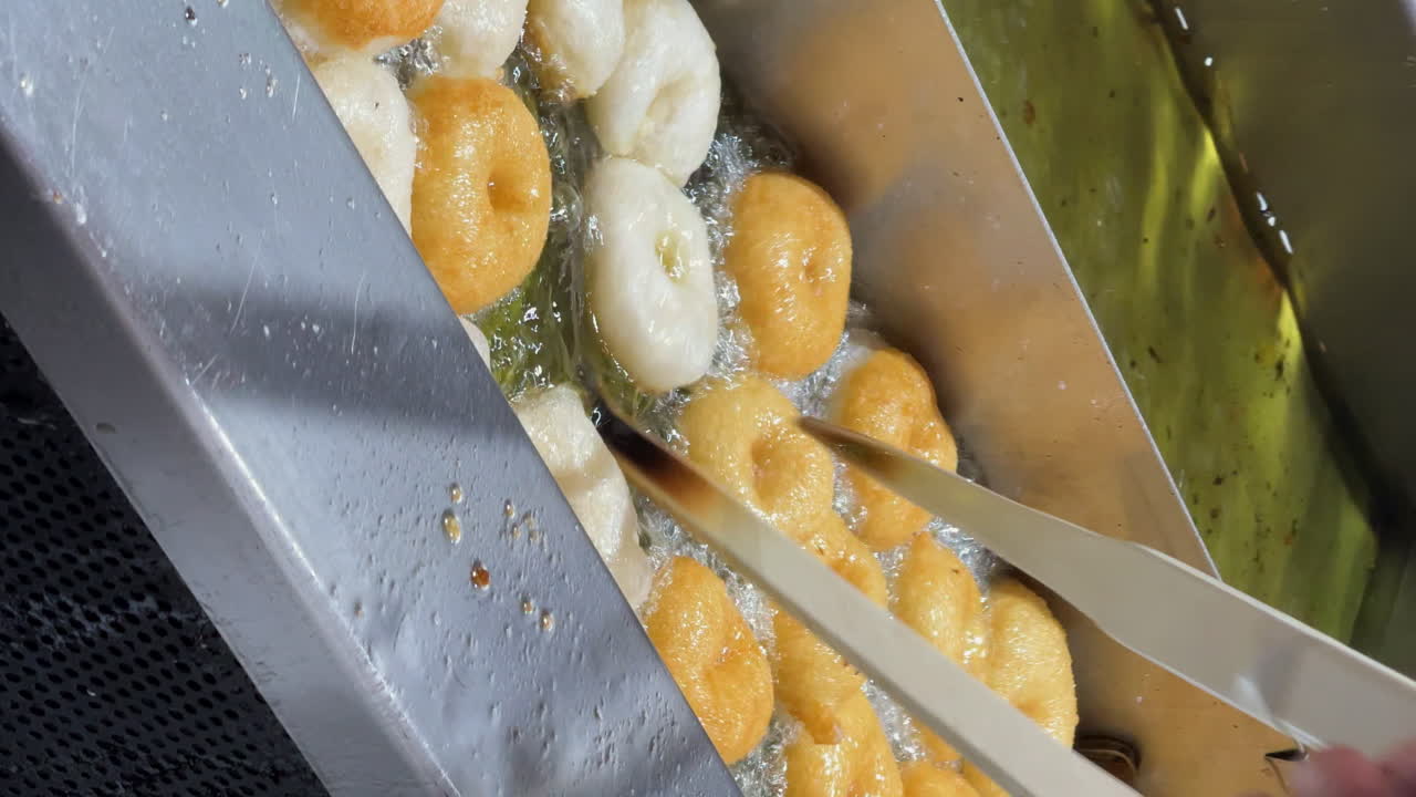 전형적인 스페인 프라이터는 호박 반죽으로 만들어집니다. 요리사는 나무 니로 그들을 뒤집습니다.