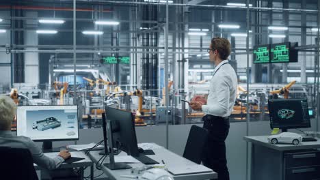 handsome engineer in glasses and white shirt using tablet computer and looking out of the office at a car assembly plant. industrial specialist working on vehicle design in technological facility.