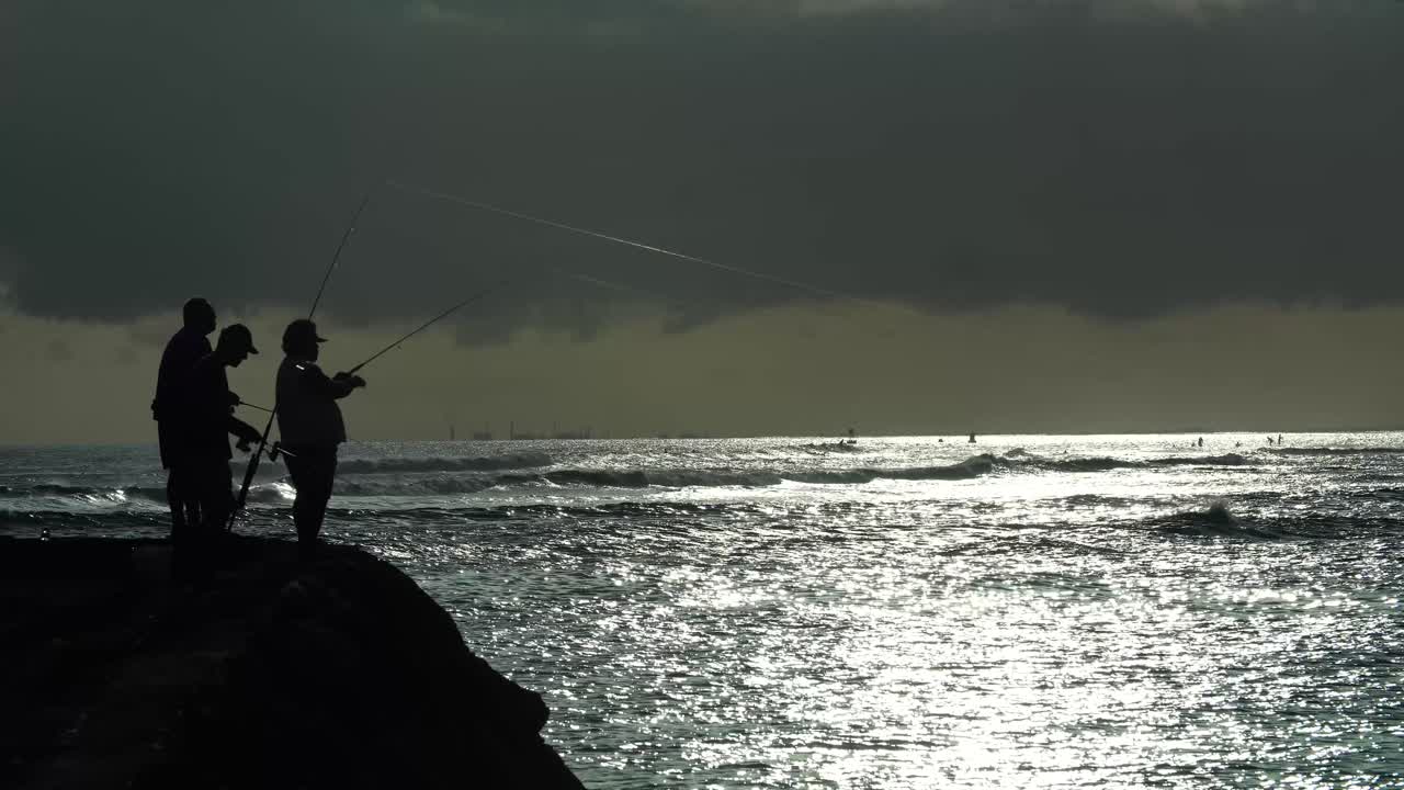 Para nelayan memancing saat matahari terbenam di Taman Pantai Ala Moana di Honolulu, Hawaii.