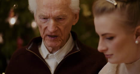 mujer enseñando al abuelo a usar el teléfono inteligente en navidad 4